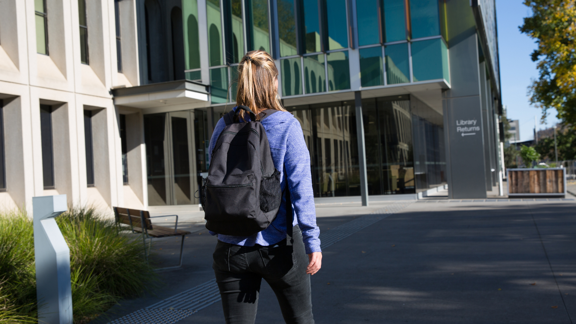a student with a backpage walking to a school building