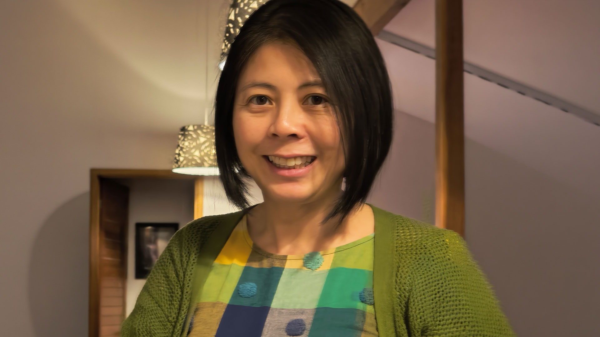 Dr Marianna Shek smiling indoors, wearing a green cardigan and patterned top
