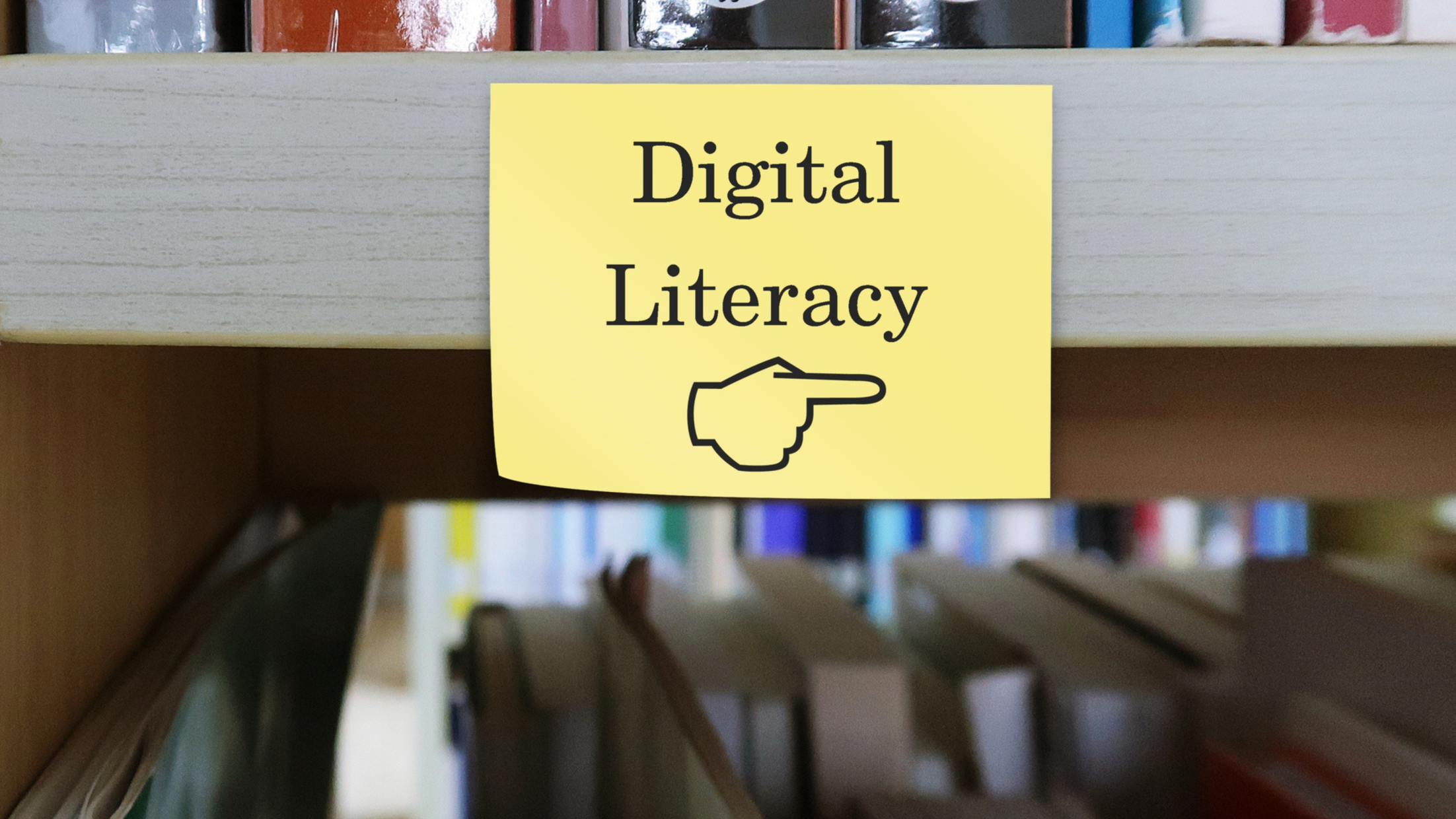 a post it note with digital literacy written on it, and a finger pointing to it