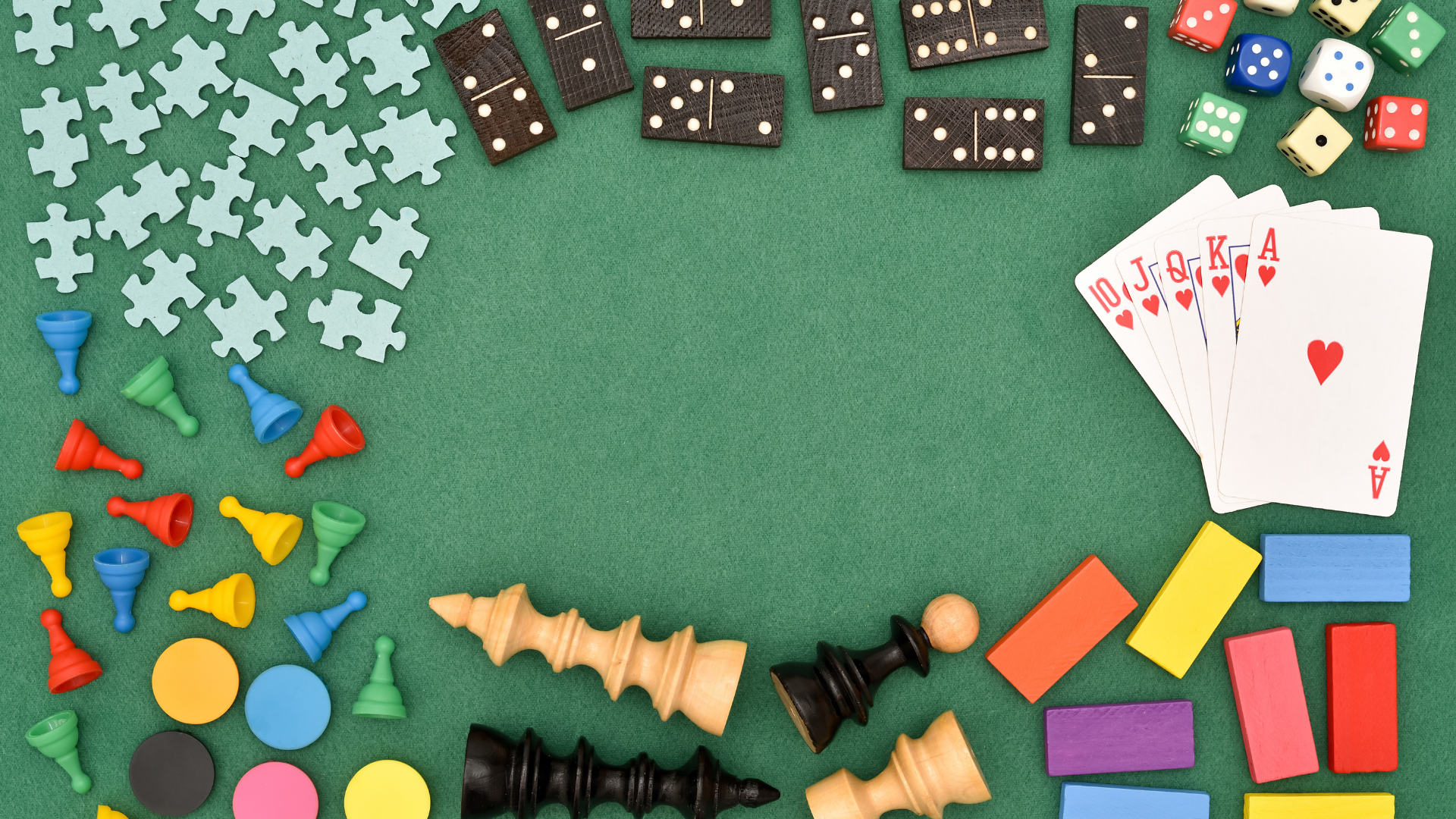 Colourful assortment of puzzles, playing cards, dice, dominoes, chess pieces and game pieces arranged around a green background.